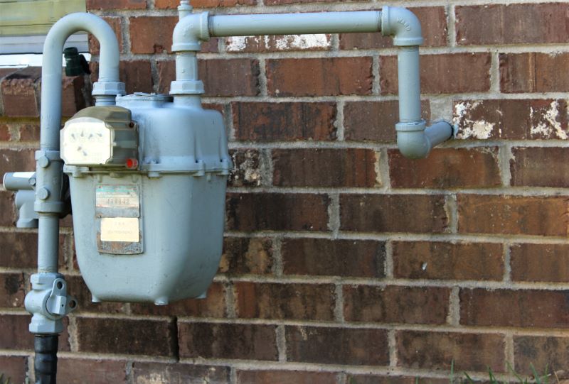 Exterior wall of a brick house showing a utility box penetration, highlighting the area where utilities enter the home.