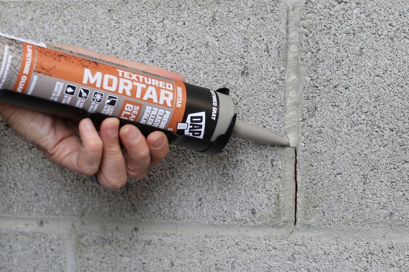 TEXTURED MORTAR being applied to the gap between cinderblocks on wall